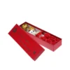 Open red gift box showing Valentine gift hamper with golden artificial rose, mini teddy bear and red soap flower arrangement