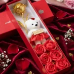 Valentine's Day gift set for girlfriend with golden rose, teddy bear and red soap flowers in luxury red box on silk fabric
